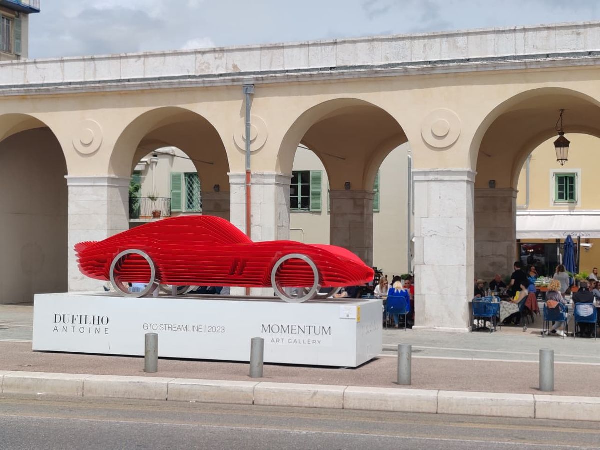 Carro clásico rojo expuesto bajo los arcos en Niza