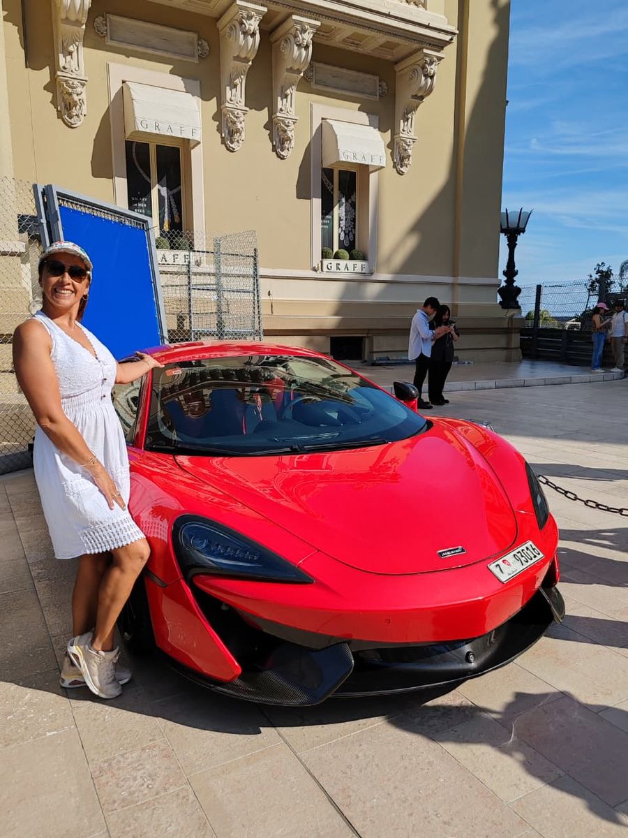 Mujer del grupo junto a un deportivo rojo frente al casino