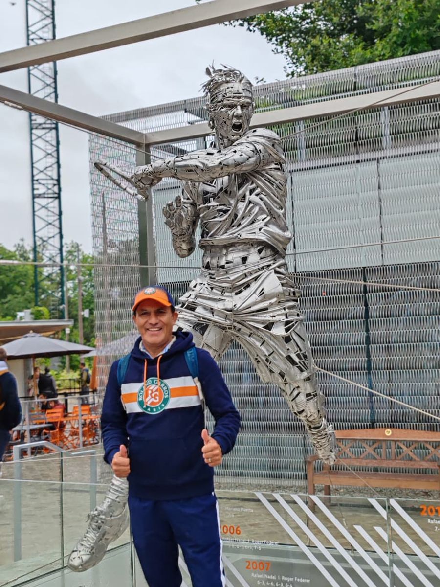 Hombre del grupo junto a la escultura metálica de un tenista